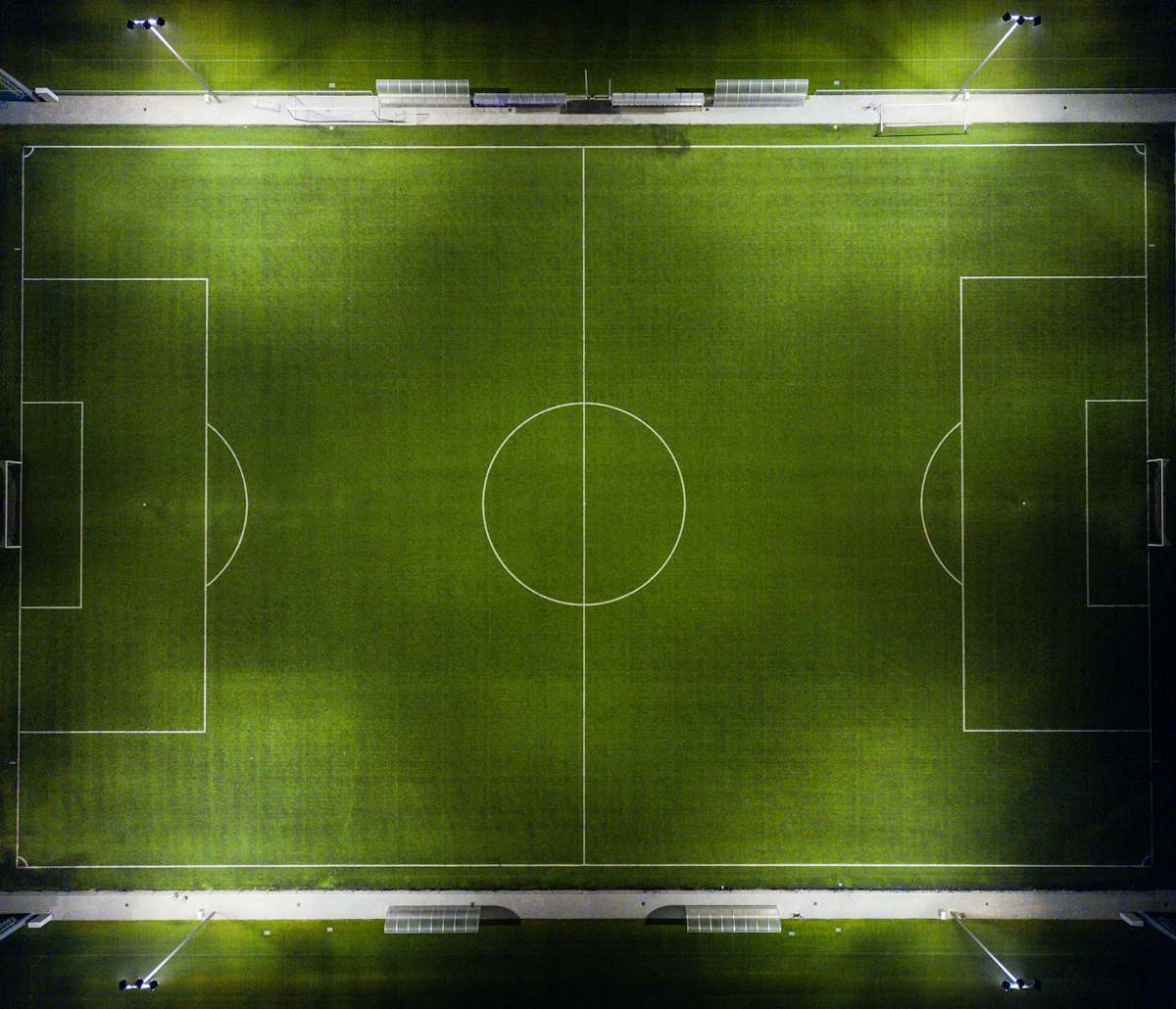 Aerial view of a floodlit soccer pitch at night