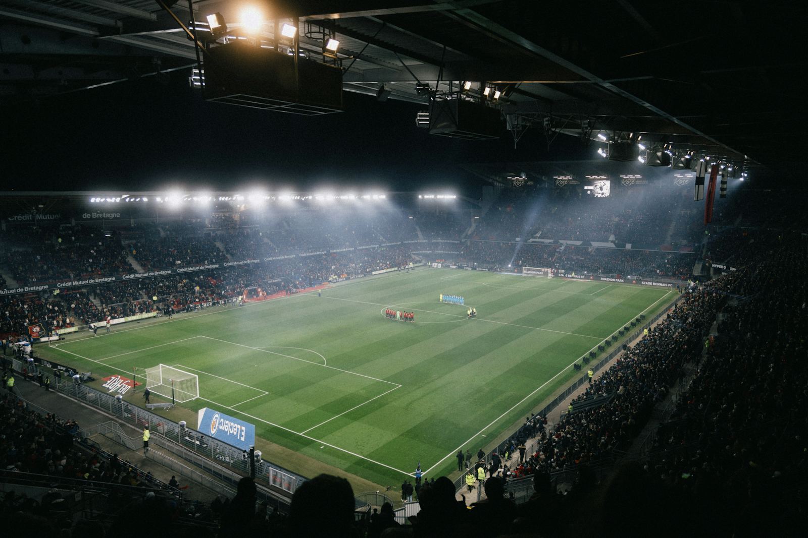 Floodlit soccer stadium at night, mist hanging over the pitch